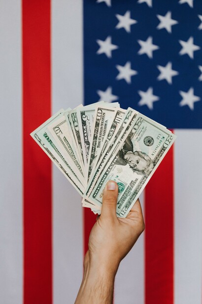 Man holding American dollars in front of the American flag