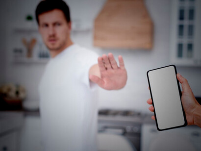 The man is actively embracing a digital detox by refusing to hold his phone, thereby reducing his screen time