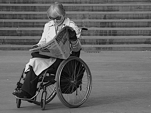 Mujer en silla de ruedas leyendo el periódico