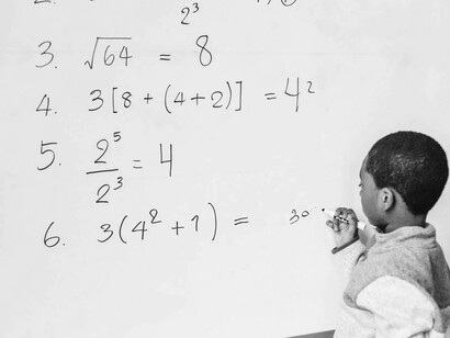 A student doing math problems on the whiteboard