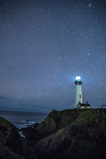 A lighthouse is surrounded by stars, still war, silence, and beauty