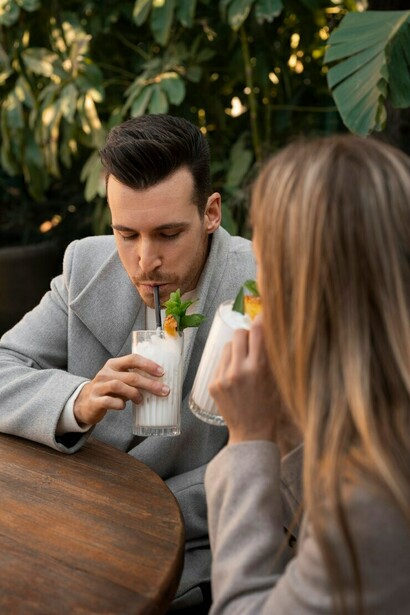A couple on their first date enjoys pina coladas at a café while browsing a dating app