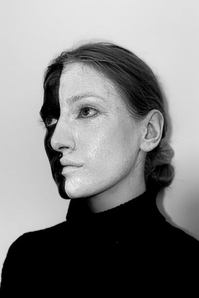 Her face is a canvas split in two: one side black, the other white, a poignant representation of the disconnection she feels within