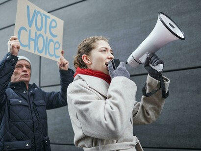 A woman holding a megaphone urging people to vote