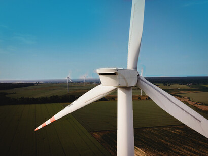A wind turbine seen from behind, and a series of fields on the background