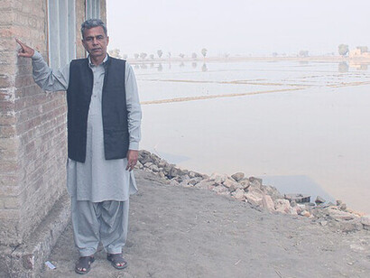 A man points to the level that the water came up to on the side of his home when floods swept through his village in Pakistan's Sindh province