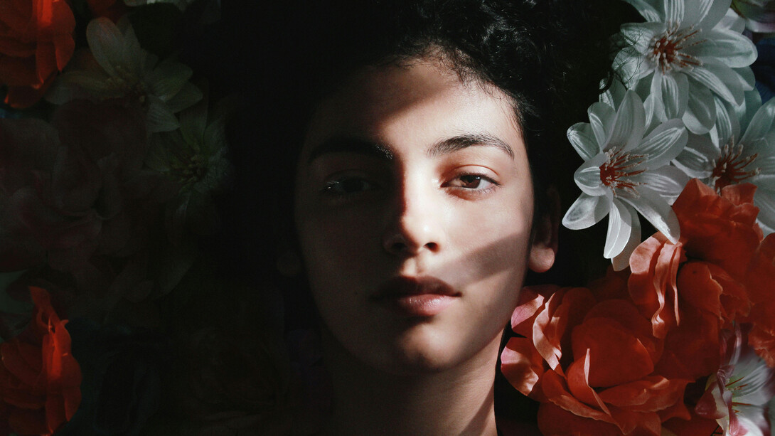 A young woman amongst flower, shadows covering one half of her face