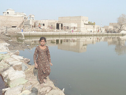 A young girl walks across a makeshift path through stagnant flood-water in Sindh province, Pakistan