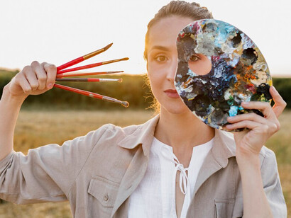 A woman holding a painting palette, radiating inner light, embarks on a spiritual journey where abstract spirituality guides her, with art serving as her salvation