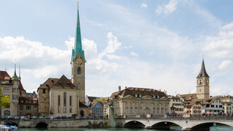 Zurich, Switzerland city view featuring Fraumünster Church, Zunfthaus zur Meisen, Münsterbrücke Bridge, and St. Peter Church in the historic Old Town skyline