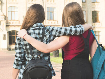 Two high school girls hugging each other, demonstrating a warm and supportive friendship