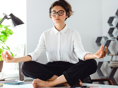 A businesswoman practicing stress relief activities at her office table, demonstrating functional wellness strategies to manage work-related stress
