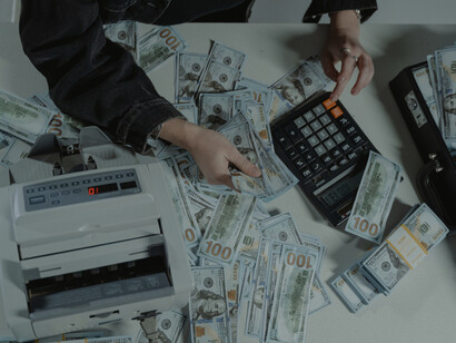 A person counting stacks of hundred-dollar bills