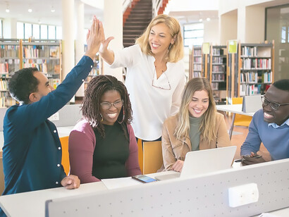 Cheerful multiethnic students having high fives with teacher