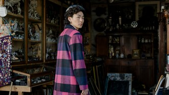 A person wearing a bold checkered coat while exploring a flea market, representing the influence of timeless fashion in a rapidly changing industry