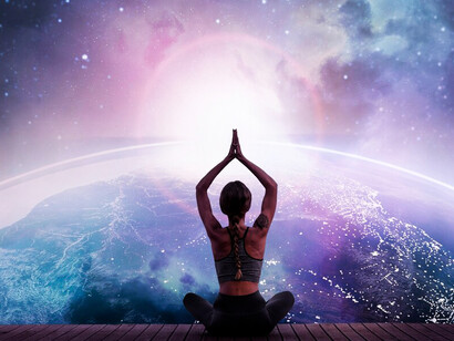 A woman sits in quiet meditation, gazing out at the vast expanse of the universe before her