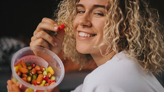 A woman in a white long-sleeve shirt holding a clear plastic container filled with colorful candies