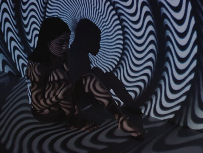 In the quiet room, a woman sat, her gaze drawn to the reflection of abstract art adorning the background