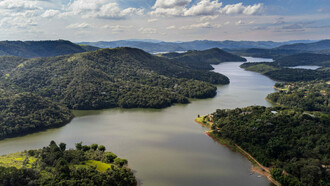 Vista aérea do reservatório Atibainha, um dos cinco lagos que compõem o sistema Cantareira, principal fonte de água potável para a cidade de São Paulo. A Mata Atlântica influencia diretamente a vida das pessoas ao fornecer água, regular o clima e proteger encostas contra deslizamentos. No entanto, a urbanização desordenada e o desmatamento continuam a ameaçar esse bioma tão importante