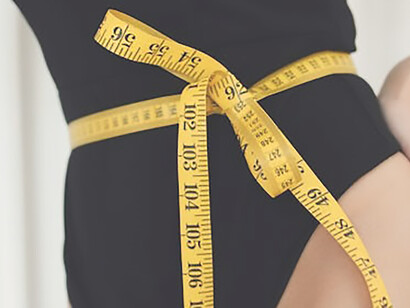 In a stunning display of transformation, a woman confidently flaunts her slender physique and the success of her weight loss journey, elegantly adorned in a chic black swimsuit, complemented by the presence of a waist meter