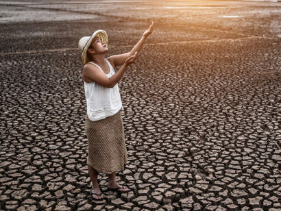 The woman stood gazing at the sky, pleading for rain to alleviate the dry conditions exacerbated by global warming