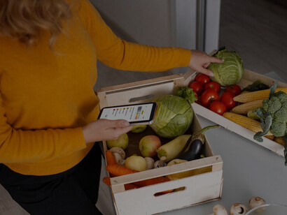 Woman checks nutritional values via barcodes on her phone while seeking a variety of vegetables