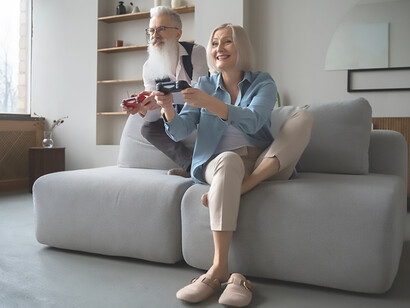 A senior couple cherishing moments of togetherness, breaking stereotypes as they enthusiastically enjoy playing together on a gaming console, proving that age is no obstacle to embracing technology and fun