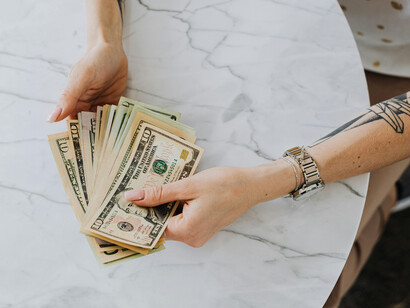 A pair of hands with a hanfdull of US dollar nbills
