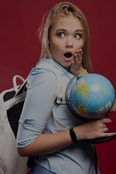 Blonde female student holding a globe and pointing to a location, embodying the spirit of international student life, cultural exchange, travel adventure, and exploring new cultures