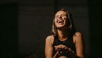 A photo of a woman laughing in a black top, capturing her funny and wonderfully weird energy