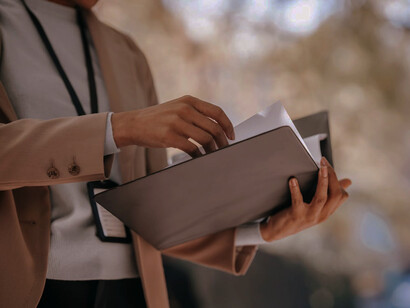 As this businesswoman sorts through files, it's clear how manual procurement methods demand significant time and effort, a challenge modern technology has effectively addressed