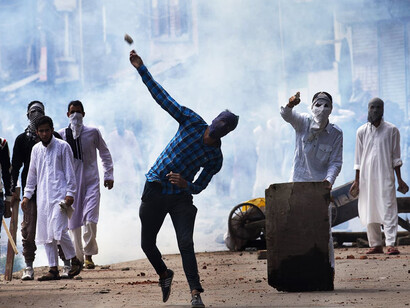 A Kashmiri throws a rock at Indian security personnel during a protest after Eid prayers