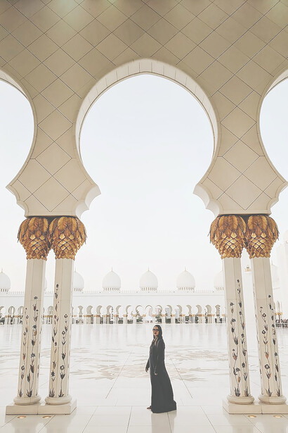 In Abu Dhabi, United Arab Emirates, a veiled woman visits the North Parking Lot of the Grand Mosque, adding her presence to the breathtaking surroundings