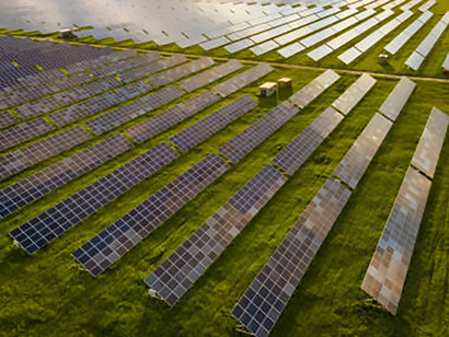 Vibrant blue solar photovoltaic panels harnessing renewable energy in a serene rural landscape, framed by a breathtaking sunset