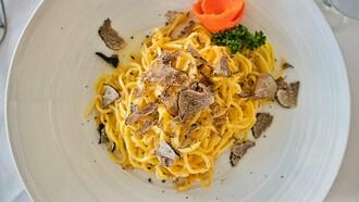 Un piatto di lusso: spaghetti arricchiti con abbondanti scaglie di pregiato tartufo nero, per un'esperienza gastronomica unica e sofisticata
