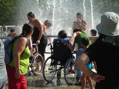 Un grupo de personas con movilidad reducida se refrescan en una fuente