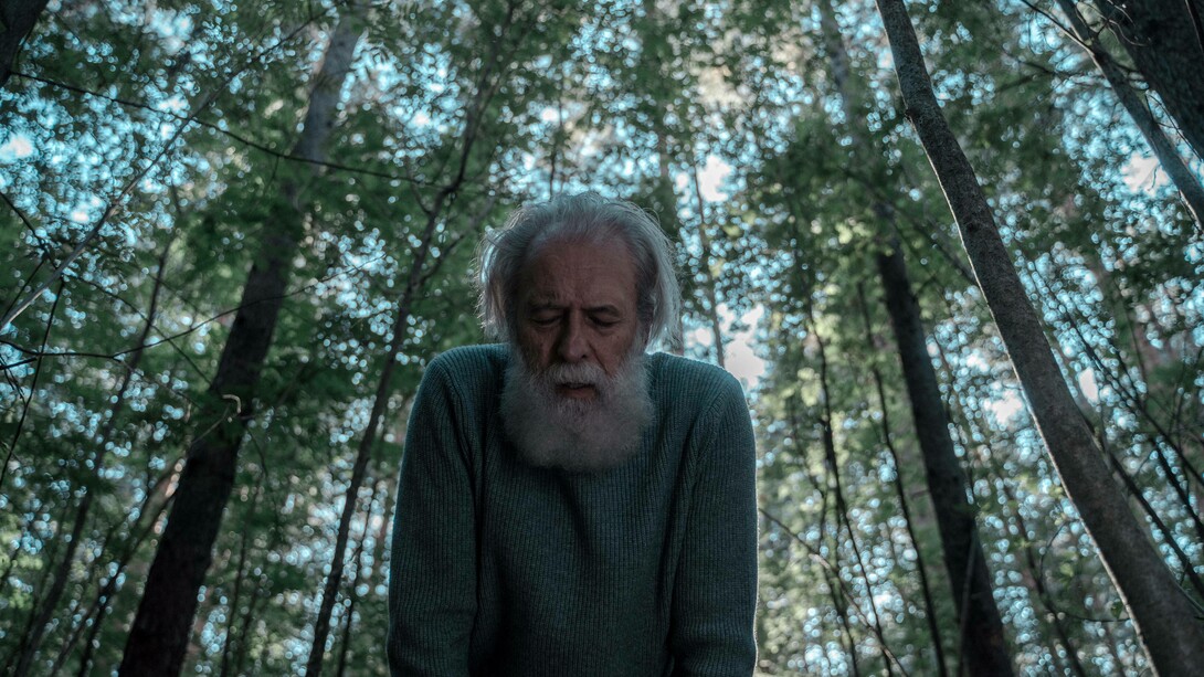 An ageing man in the forest trying to catch his breath