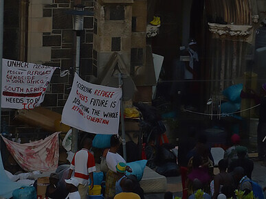 Refugee protesters gather outside the Old Townhouse near the Central Methodist Church, mirroring the ongoing occupation both indoors and outdoors, South Africa