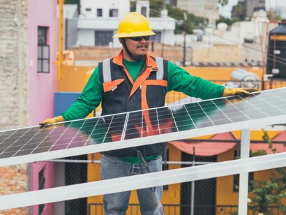 A construction worker holding an energy-efficient solar panel