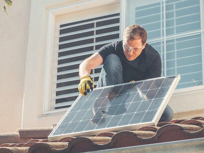 A homeowner is seen installing solar panels on his house to harness renewable solar energy