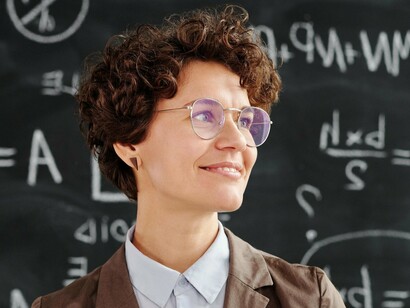 A young woman before a blackboard looking pleased after solving a problem posed by the teacher