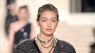 Modelo usa brincos Chanel, colares de pérolas e com detalhes pretos e dourados