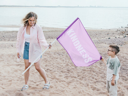 A mother and son holding up kindness on the beach