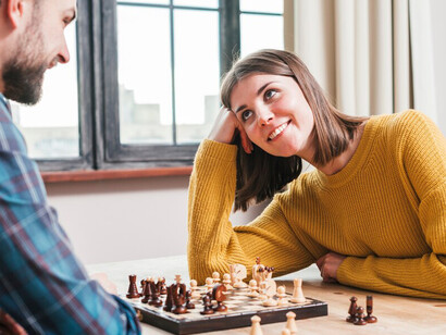 A young man playing chess with his wife at home for a fun and strategic game night