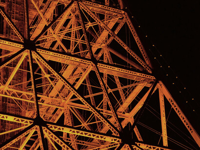 A close up of the Eiffel Tower's structure, illuminated at night