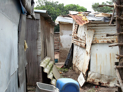 Inside a cramped township dwelling, residents struggle with basic living conditions amidst a backdrop of historical land injustice