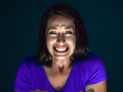 A woman staring at the screen with a look of fear and shock