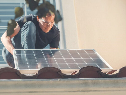 A man is installing solar panels on his house to harness solar energy
