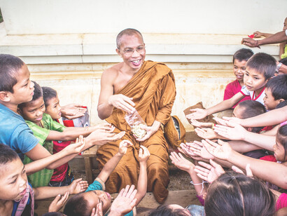 A happy monk sharing with the children