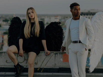 A man and woman dressed in contrasting black and white angel costumes, symbolizing the duality of good and evil